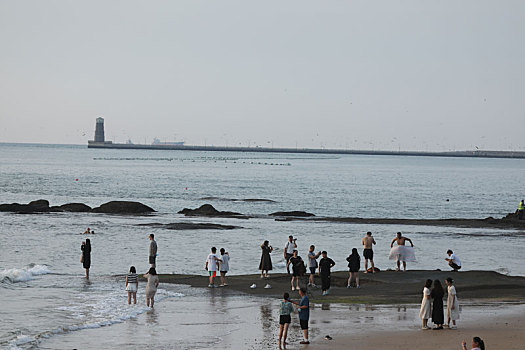 山东省日照市,清晨里的灯塔风景区凉爽宜人,游客漫步沙滩享受惬意生活