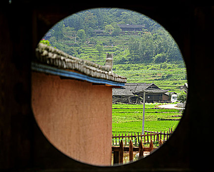 透过圆形窗户看南方稻田间的小村庄