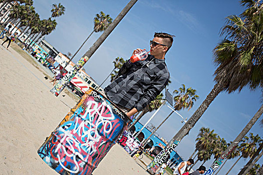 倾斜视角,少男,喝,冰沙,靠近,涂鸦,遮盖,垃圾桶,洛杉矶,加利福尼亚,美国