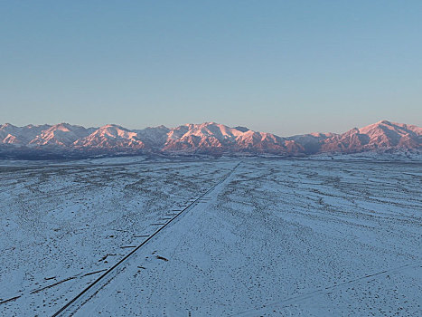 新疆哈密,落日余晖下雪映金色天山