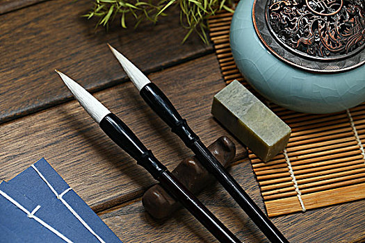 毛笔,线装书和香炉放在竹帘和木桌上