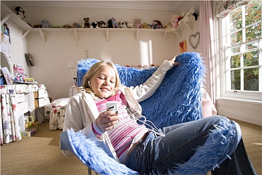 女孩,8-10岁,坐,蓝色,粗毛,堆,椅子,听,mp3播放器,微笑