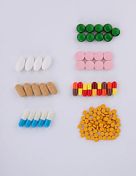 俯视不同颜色形状的药丸和胶囊规整放在白桌面上