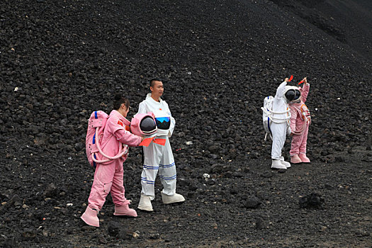 内蒙古火山口游客穿宇航服拿国旗拍照,宛若登陆外星球