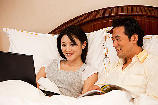 年轻夫妻躺在床上使用电脑