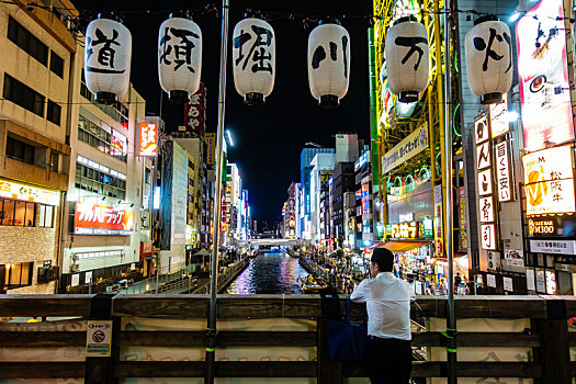 夜晚人们在日本大阪道顿堀川万灯祭的灯笼下欣赏风光