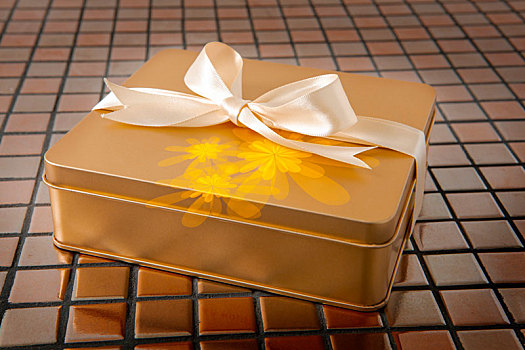绑上缎带的金色礼盒在磁砖的背景上