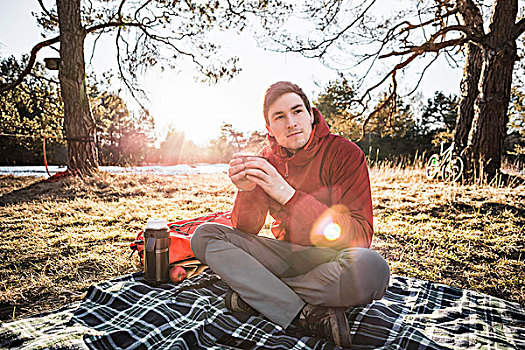 男青年,坐,野餐毯,喝咖啡,树林