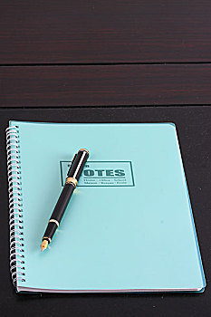 一个合着的的笔记本和一支钢笔