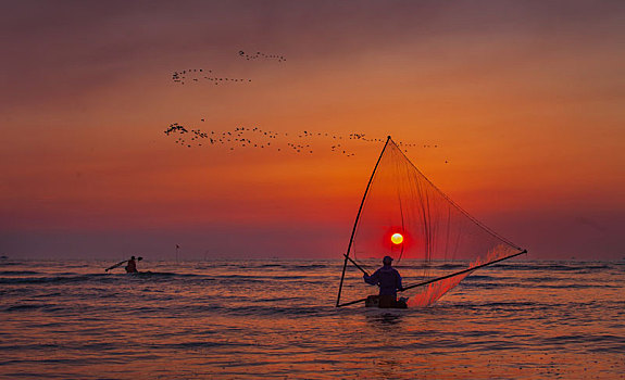 逆光拍摄的沿海渔民