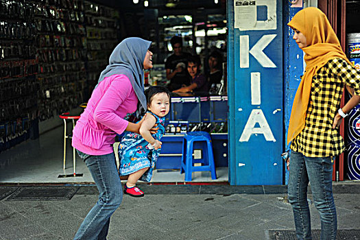 indonesia,sumatra,banda,aceh,two,veiled,woman,playing,with,child,in,the,street