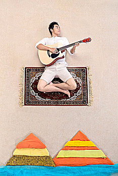 坐在魔毯上弹吉他的男士