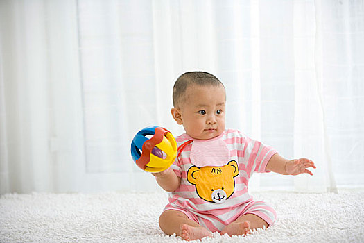 一个在地毯上玩玩具的婴儿