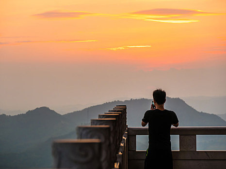 游客正在惠州高榜山挂榜阁用手机拍摄夕阳场景