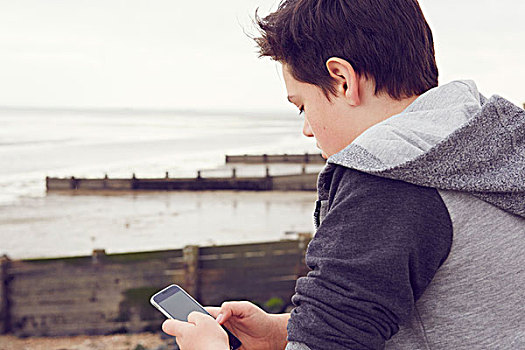 少男,海边,发短信,智能手机,海洋,艾塞克斯,英国