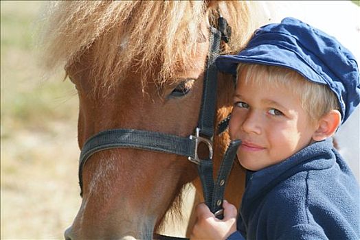 肖像,男孩,姿势,微笑,拿着,小马,缰绳,蓝色,帽子,外套