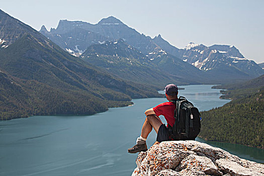 男性,远足者,背包,坐,石头,悬崖,远眺,湖,山峦,蓝天,沃特顿,艾伯塔省,加拿大