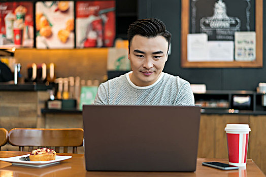 年轻男子在餐厅使用电脑