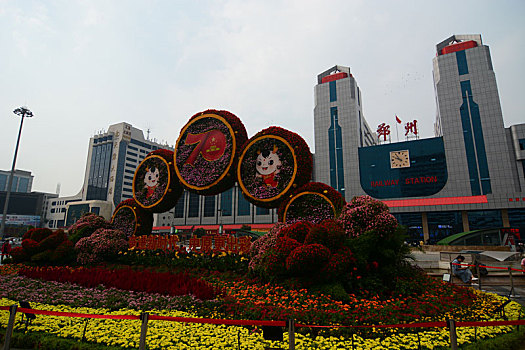 19年10月拍摄于河南省郑州火车站东广场,匆忙的行人,没有人的郑州站地标标志,和庆祝70年崛起新中原地区的园艺景观