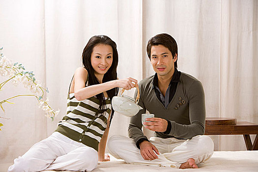 一对年轻夫妻坐在床上喝茶