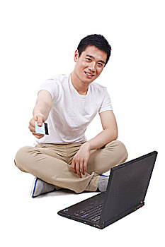 一个盘腿坐着看电脑手拿银行卡的男青年