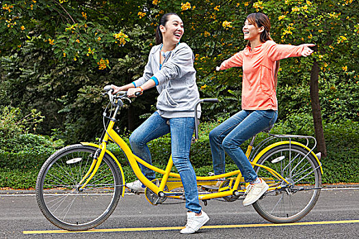 两个年轻女大学生在校园里骑车