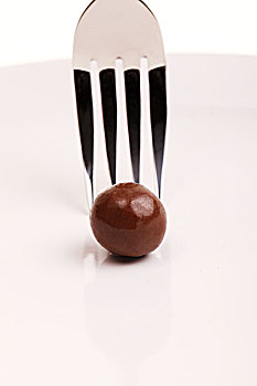 用银色叉子叉一个圆形棕色巧克力
