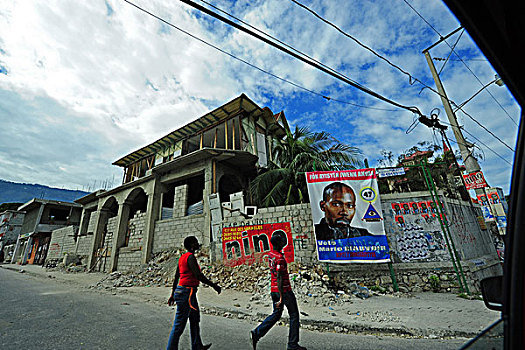 haiti,port,au,prince,young,adults,walking,by,presidential,campaign,advertisement