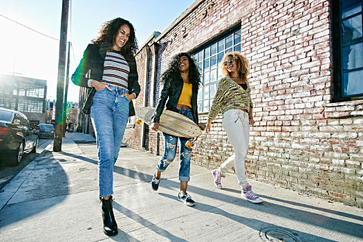 三个女人,年轻,长,卷发,走,人行道,一个,滑板