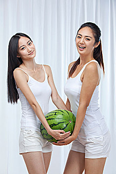 两个健康快乐的亚洲女孩拿着西瓜