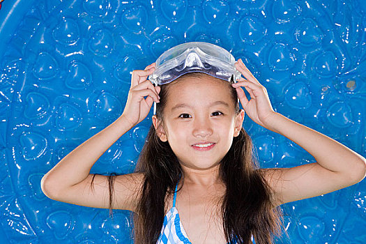 穿著泳衣戴著潛水鏡的小女孩對著鏡頭微笑