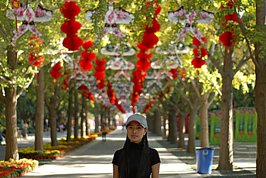 一名年轻女性站在挂满红色灯笼的街道上