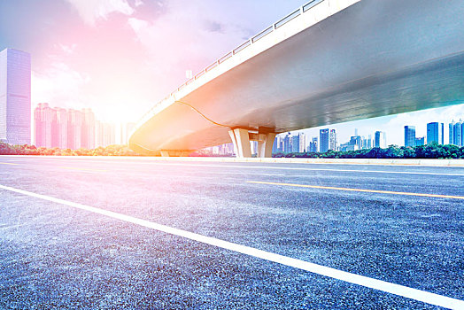 立交桥下,无车的沥青道路,现代城市建筑天际线为背景