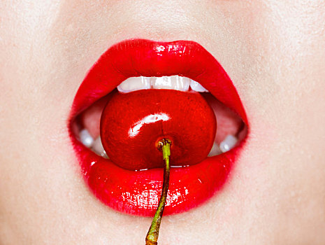 美妆红唇里含咬着一个樱桃的特写