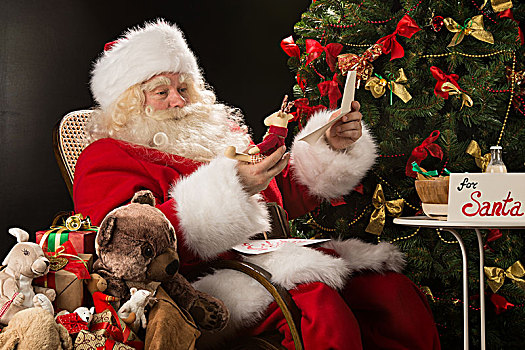 圣诞老人,坐,在家,舒适,扶手椅,拿着,信封,读,信,愿望,选择,玩具,大,袋,靠近