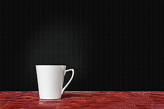 白色杯子,暗红桌面,黑色背景