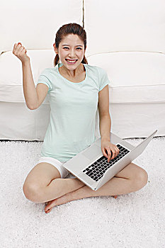 年轻女士坐在沙发旁拿着电脑