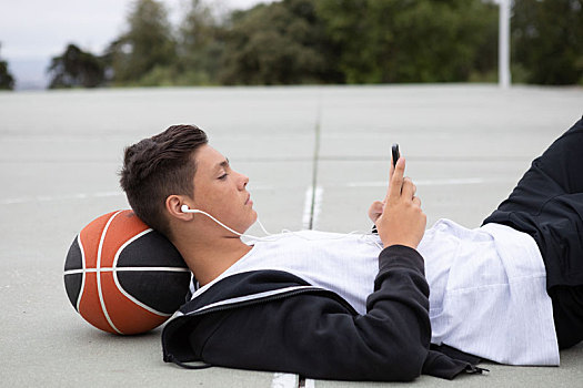 男性,青少年,篮球手,躺着,篮球场,看,智能手机