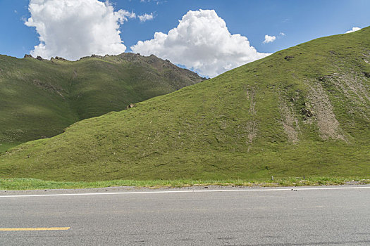 中国新疆夏季蓝天白云下高山草原g217独库公路直行道侧面