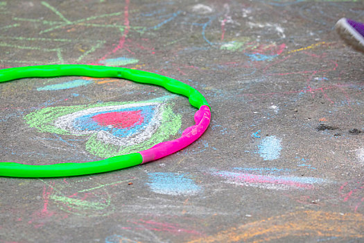 小孩在室外的公园地板上,用粉笔快乐的涂鸦画画