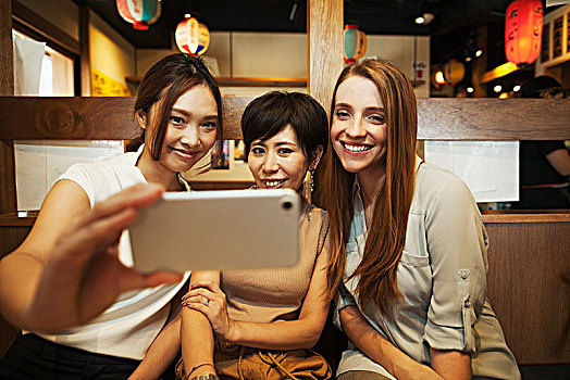 三个女人,坐,并排,餐馆,智能手机