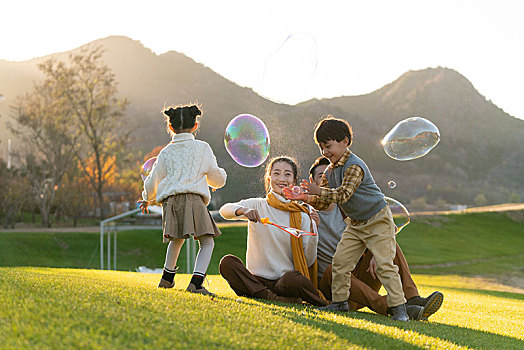 年轻夫妻和孩子们在草地上玩泡泡