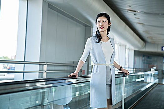 年轻商务女士在机场乘坐移动电梯