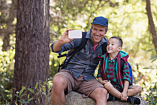 高兴,父亲,坐,男孩,岩石上,手机,树林