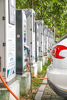 新能源汽车充电站的充电桩和正在充电的汽车