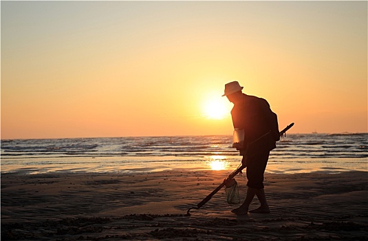 山东省日照市,老人扛着锄头扒蛤蜊,清晨里的海边风景如画