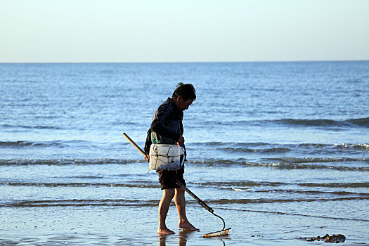 渔民迎着金色霞光赶海拾贝,成为海滩上的靓丽风景