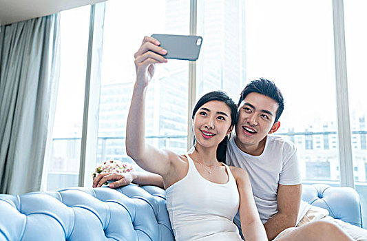 年轻情侣在沙发上使用手机