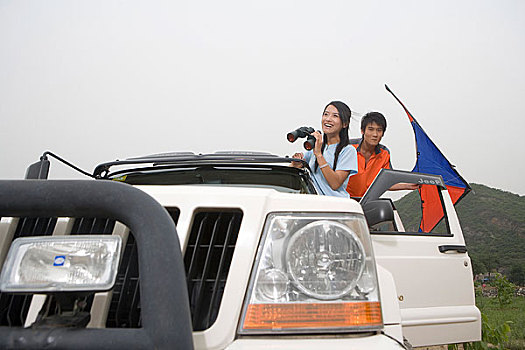 一对年轻的夫妻开着越野车在郊外放风筝