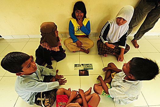 indonesia,sumatra,banda,aceh,group,of,children,looking,at,photographs,during,art,in,all,us,activities